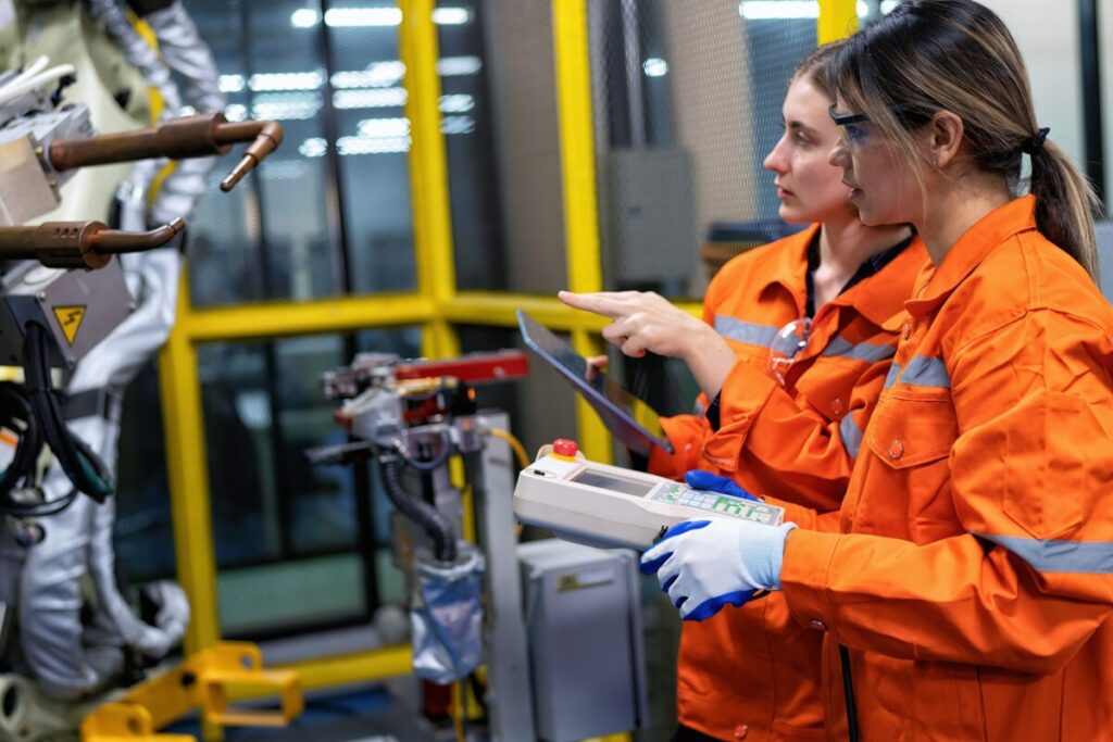 Girl engineer commissioning operating programming and looking at robot machine in the factory